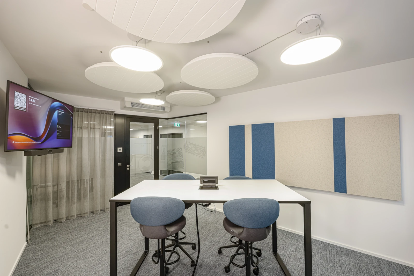 Besprechungsraum Compass Verlag mit Stehtisch, Akustik-Deckensegeln und Wandabsorber in Blau und Beige