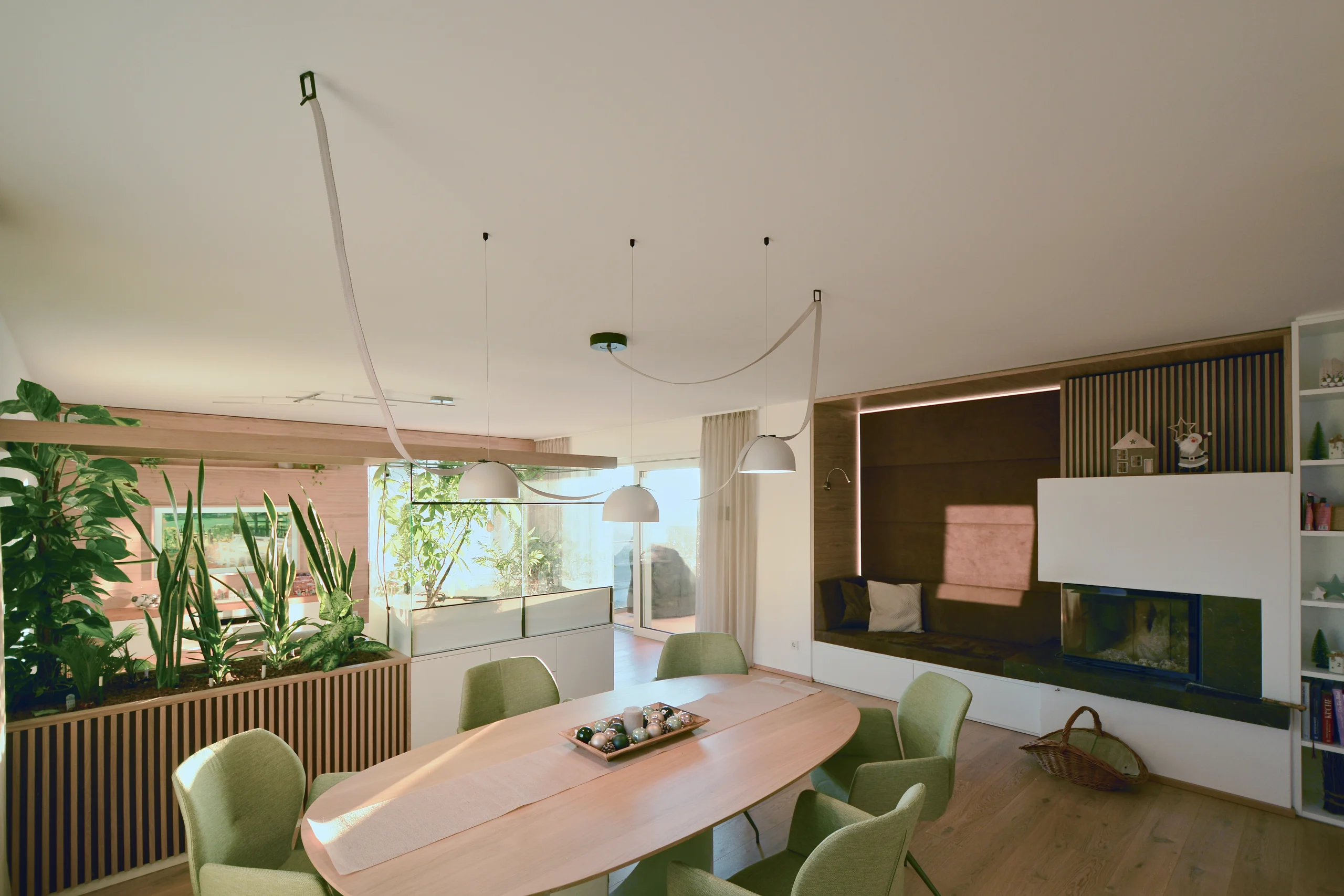Wohnraumplanung: Essbereich mit ovalem Eichentisch, Sitznische mit Lichtfuge und Kamin, Pflanztrog mit Holzlamellen – geplant von ELIAS raumdesign